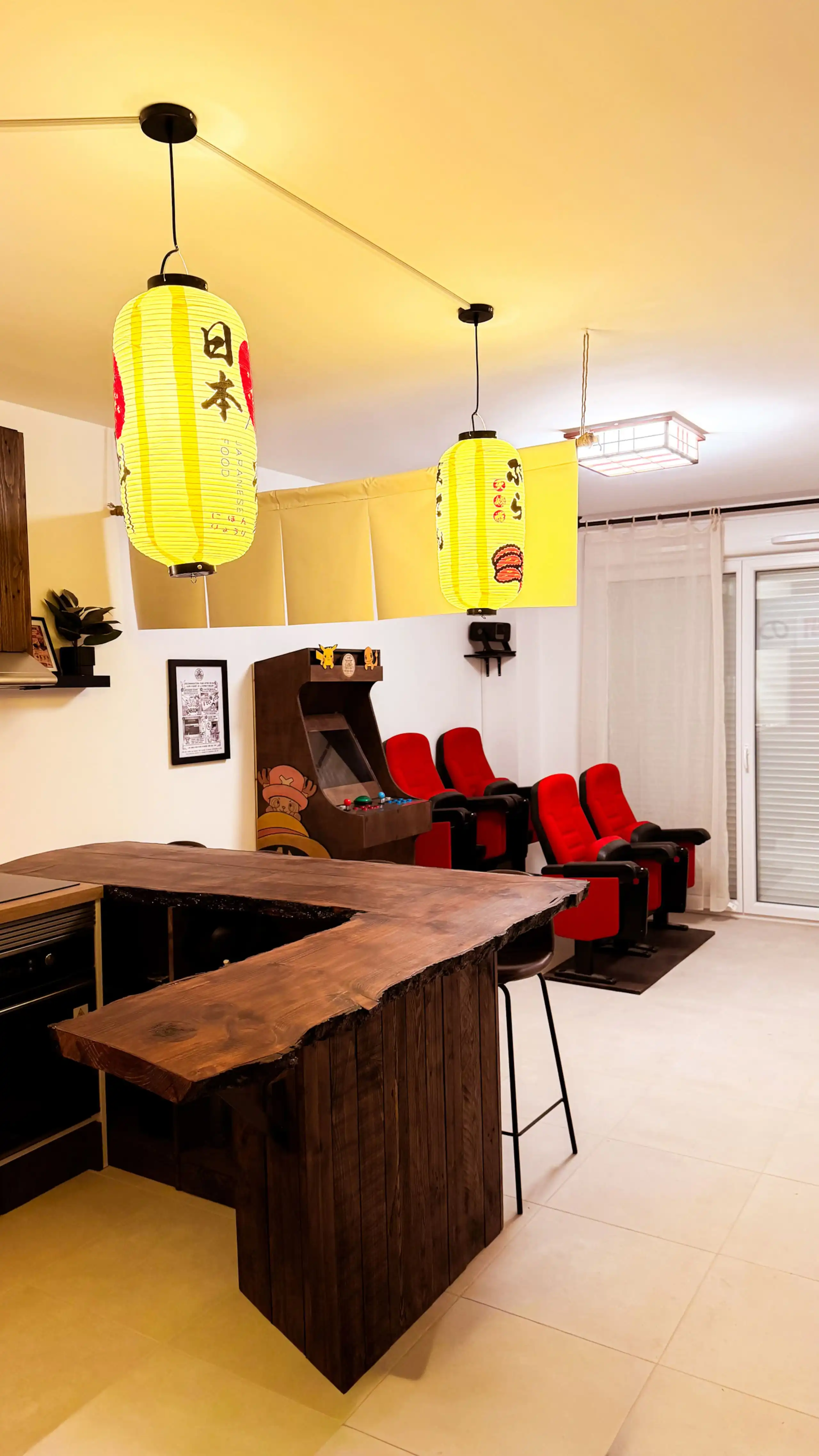 The living room at Nakama House with its genuine red cinema seats, wooden arcade cabinet and Japanese lanterns — photo 1